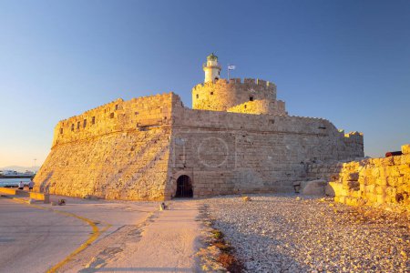 Das antike Fort des Heiligen Nikolaus am Eingang des Hafens von Mandraki auf Rhodos, Griechenland bei Sonnenuntergang