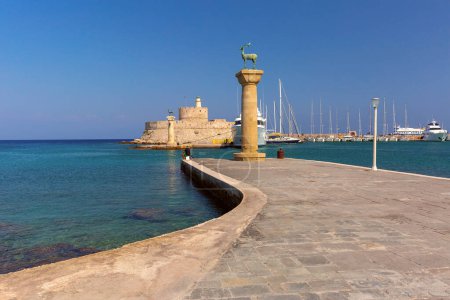 Panoramic view of Mandraki Harbor in Rhodes, Greece, with deer statue and clear blue waters