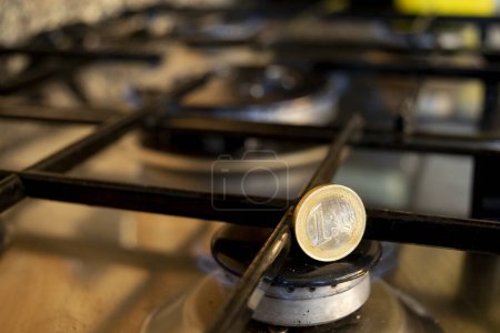 Téléchargez les photos : Pièce de 1 euro sur une cuisinière à gaz comme concept de coût énergétique - en image libre de droit