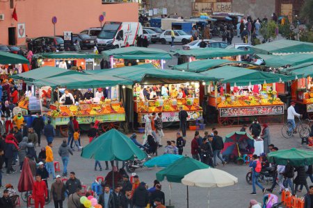 Foto de MARRAKECH, MARRUECOS - 20 DE FEBRERO DE 2022: La gente visita Jamaa el-Fnaa mercado cuadrado de la ciudad de Marrakech, Marruecos. La plaza está catalogada como la obra maestra de la UNESCO de Patrimonio Inmaterial de la Humanidad. - Imagen libre de derechos