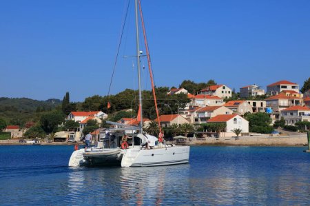 Photo for KORCULA, CROATIA - JULY 15, 2021: Lagoon 410 catamaran departing from Lumbarda Marina in Korcula Island. Croatia is a famous summer sailing destination in Europe. - Royalty Free Image