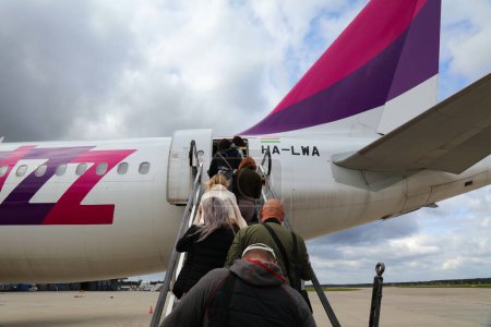 Foto de KATOWICE, POLONIA - 24 DE SEPTIEMBRE DE 2021: Pasajeros a bordo de la aerolínea de bajo coste Wizz Air Airbus A320 por escaleras en el aeropuerto de Katowice en Polonia. - Imagen libre de derechos