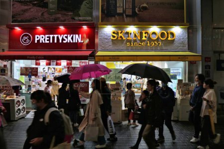 Téléchargez les photos : SEOUL, CORÉE DU SUD - 5 AVRIL 2023 : Les gens visitent les magasins de beauté coréens Prettyskin et Skinfood dans le quartier commerçant de Myeongdong à Séoul la nuit tombée. - en image libre de droit