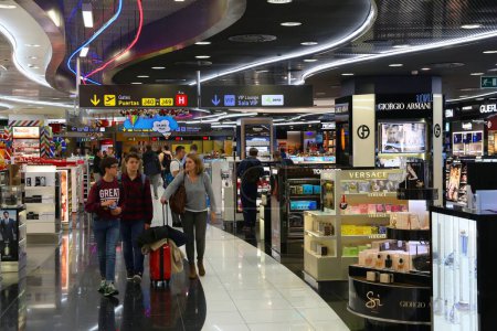 Téléchargez les photos : MADRID, ESPAGNE - 6 DÉCEMBRE 2016 : Les passagers visitent les boutiques hors taxes de l'aéroport de Madrid Barajas en Espagne. C'est l'un des aéroports les plus fréquentés d'Europe. Il est géré par AENA. - en image libre de droit
