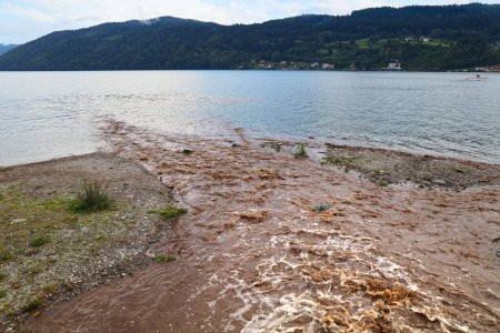 Téléchargez les photos : Un ruisseau d'eaux pluviales boueuses rejoint Millstatter See (lac Millstatt) en Carinthie. - en image libre de droit