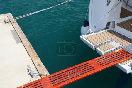 Sailing in Split, Croatia. Sailing yacht wooden boarding gangway walking bridge (passerelle) mounted to the stern of the boat in a marina.