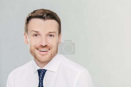 Photo for Studio shot of handsome unshaven male entrepreneur with cheerful expression, rejoices raising sales, dressed in formal clothes, isolated over white background with copy space aside for your text - Royalty Free Image