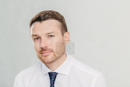 Photo for Serious attractive man dressed in elegant clothing, has stubble, feels self confident, looks pensively directly at camera, poses against white background. People, business, occupation concept - Royalty Free Image
