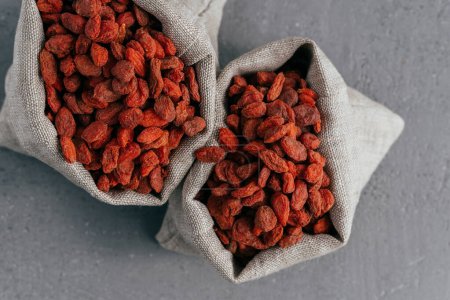 Photo for Dry superfood goji berries for healthy eating in two burlap sacks isolated over grey background. Food supplement. Red wolfberries in bags - Royalty Free Image