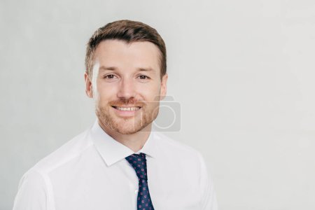 Photo for Headshot of attractive unshaven young male with cheerful expression, looks confidently at camera, being pleased to meet with colleagues, dressed in formal clothes, isolated over white background - Royalty Free Image