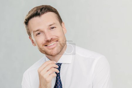 Photo for Satisfied male worker with positive expression, has broad smile, rejoices sucessful agreement with partner, wears elegant clothes, isolated over white studio wall. People, positive emotions concept - Royalty Free Image