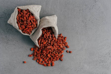 Photo for Healthy goji berries spilled out of small sack, isolated over grey background. Agriculture and nutrition concept. Superfood - Royalty Free Image