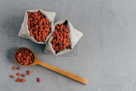 Photo for Isolated shot of dry red goji berries in two small sacks and on wooden tablespoon. Top view. Super food with antioxidants, minerals and vitamins - Royalty Free Image
