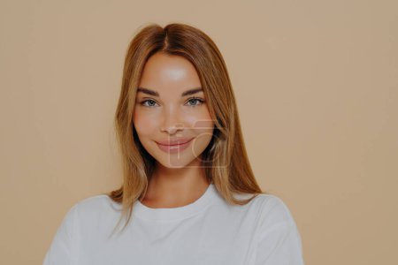 Photo for Close up portrait of young smiling beautiful woman with long straight hairstyle, wearing white casual tshirt, looking at camera with joy, mysterious smile. Human facial expressions and emotions - Royalty Free Image