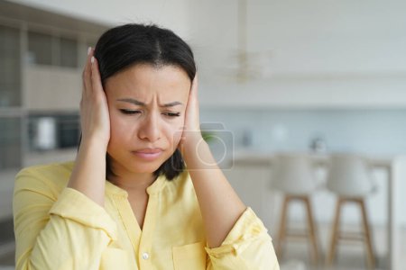 Upset angry female tenant cover ears with hands ignore noise at home. Irritated frustrated woman suffer from loud music, tired from noisy neighbors in apartment. Family conflict concept.