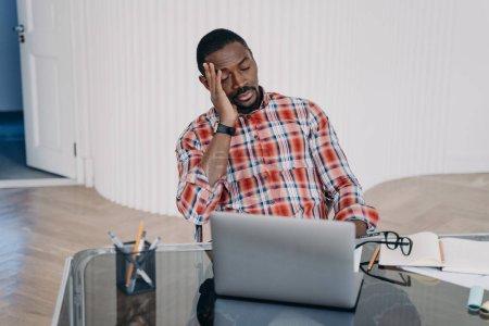 Téléchargez les photos : Upset tired african american businessperson hold head with hand have problem in work. Black guy businessman closed eyes sitting at office desk at laptop. Difficulties in job, professional burnout. - en image libre de droit