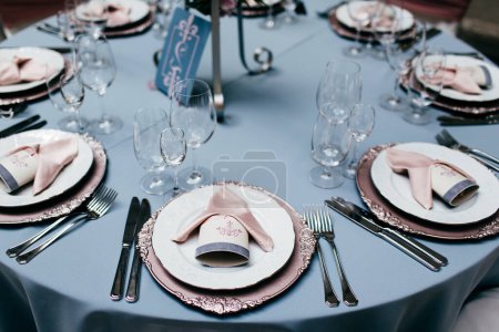 Photo for Table appointments. Table setting with empty plates, forks, glasses and knives and light blue tableclothes. Served table in restaurant for special occasion. Cafe or restaurant set. - Royalty Free Image