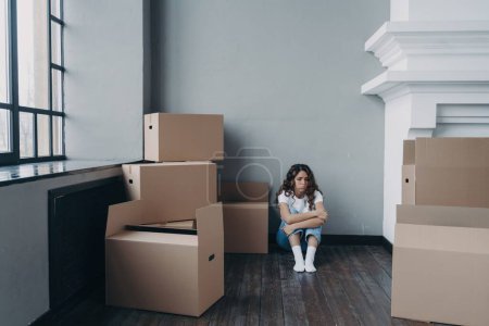 Foto de Triste mujer sentada en medio de cajas llenas en una habitación vacía, sintiendo desesperación. Abrumado por el divorcio o el desalojo. - Imagen libre de derechos