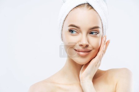 Photo for Model with makeup, touches cheek, fresh skin after bath, towel on head, isolated - Royalty Free Image