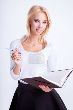 Téléchargez les photos : Portrait d'une jolie jeune femme blonde adulte écrivant dans un cahier isolé sur fond blanc - en image libre de droit