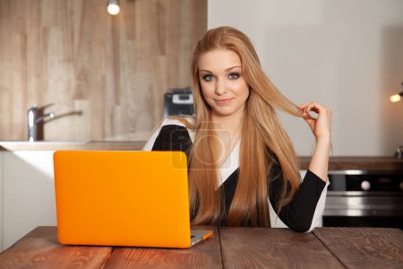 Téléchargez les photos : Portrait d'une jolie jeune étudiante blonde adulte qui travaille sur l'ordinateur orange - en image libre de droit