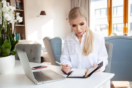 Photo for Portrait of young adult attractive blonde businesswoman in white shirt working in home office - Royalty Free Image