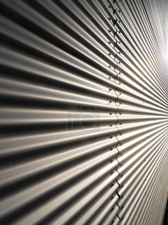 Un mur métallique avec une série de bandes métalliques. Les bandes sont pliées et tordues, créant un sentiment de mouvement et d'énergie. Le mur semble être en métal, ce qui lui donne un aspect moderne et industriel.