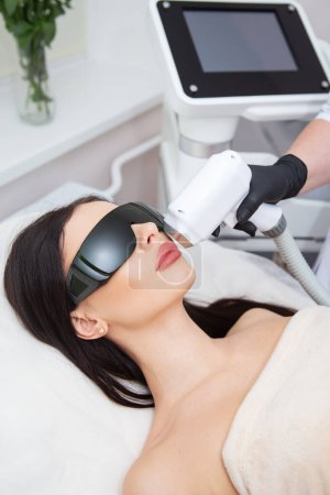 The process of laser hair removal of the female body. professional cosmetology, epilation of the face and upper lip area. Girl in goggles. Body care concept