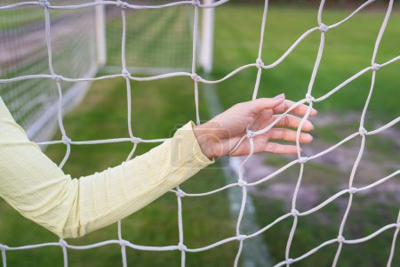 Photo for A girl stands near a white net close-up on a soccer field, a soccer goal. Green field - Royalty Free Image