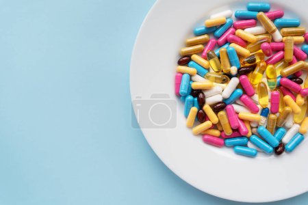 Foto de Pastillas de colores en un tazón blanco grande sobre un fondo azul. El concepto de salud y medicina basada en la evidencia - Imagen libre de derechos