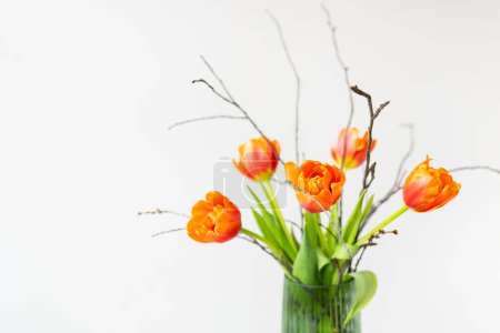 A very beautiful spring bouquet in a green vase stands on a table on a linen tablecloth, orange peony tulips. Mother's Day, March 8, Valentine's Day. Place for an inscription