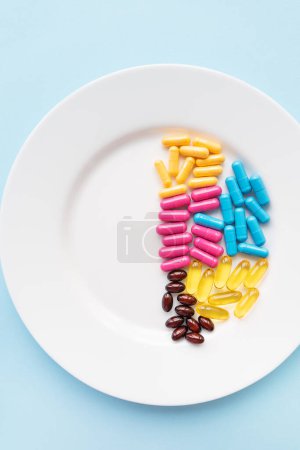 Photo for Food supplements-capsules of bright color lie on a white plate in a heap. Concept of medicine and health - Royalty Free Image