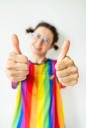 Foto de Retrato de cerca de una chica coqueta bastante alegre con una camiseta a rayas brillantes, bandera LGBT, mostrando un doble ok, como signo - Imagen libre de derechos