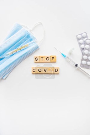 Photo for Stop coronavirus inscription. A new strain of coronavirus-omicron, pyrola. Preparing for vaccination against covid. Syringe, vaccine, pills, medical mask - Royalty Free Image