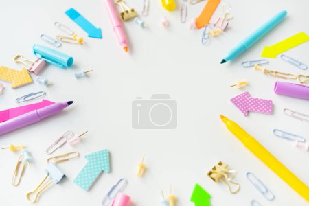 Téléchargez les photos : Colorful assortment of office supplies including pens, markers, paper clips and paper clips scattered on a white background. The overall mood is bright and creative, with space for writing - en image libre de droit