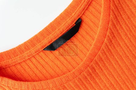 A close-up of the orange ribbed sweater's neckline, highlighting the texture and quality of the fabric