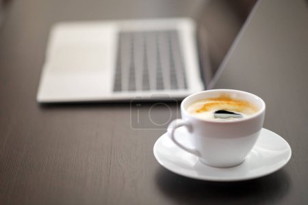 Foto de Taza de café con portátil en la mesa de madera en la cafetería - Imagen libre de derechos