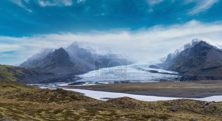 Photo for Glacier tongue slides from the Vatnajokull icecap or Vatna Glacier near subglacial Oraefajokull volcano, Iceland. Glacial lagoon with ice blocks and surrounding mountains. - Royalty Free Image