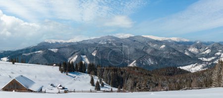 Photo for Picturesque snowy winter mountain slope and lone farmhouse on plateau farmstead, Carpathian, Ukraine. Chornohora ridge panorama and Pip Ivan mountain with observatory on top in clouds behind. - Royalty Free Image