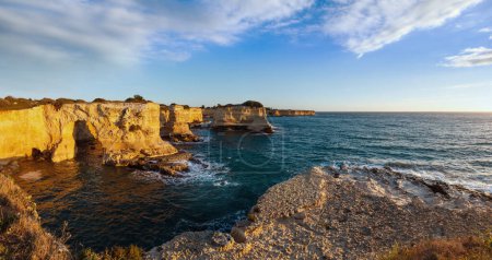 Photo for Picturesque seascape with cliffs, rocky arch and stacks (faraglioni), at Torre Sant Andrea in morning sunlight, Salento sea coast, Puglia, Italy. - Royalty Free Image