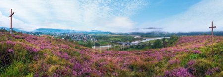 Photo for Summer misty morning country foothills panorama with heather flowers and wooden cross (Lviv Oblast, Ukraine). - Royalty Free Image