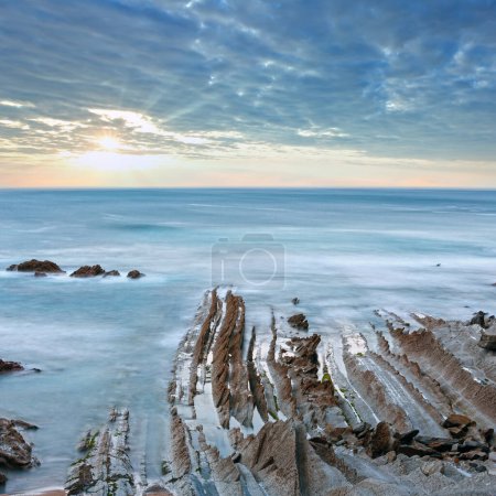 Foto de Costa oceánica crepuscular con formaciones rocosas estratiformes acanaladas. (Océano Atlántico, España). - Imagen libre de derechos