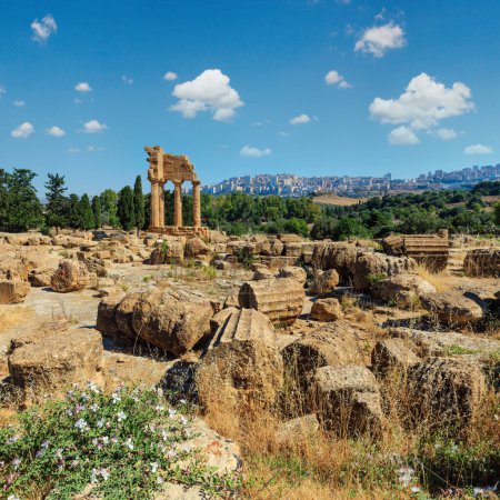 Foto de Templo de Dioscuri (Castor y Pollux) con la ciudad de Agrigento en el fondo. Famosas ruinas antiguas en el Valle de los Templos, Agrigento, Sicilia, Italia. Patrimonio de la Humanidad UNESCO
. - Imagen libre de derechos