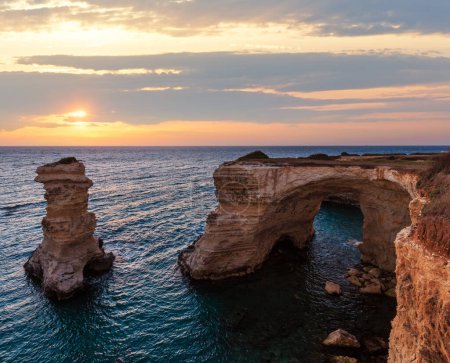 Foto de Crepúsculo paisaje marino con acantilados, arco rocoso y pilas (faraglioni), en Torre Sant Andrea, costa del mar de Salento, Puglia, Italia - Imagen libre de derechos