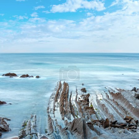 Photo for Twilight ocean coast with ribbed stratiform rock formations. (Atlantic Ocean, Spain). - Royalty Free Image