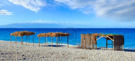 Foto de Summer morning beach with sunbeds, canopies and white pebble (Borsh, Albania). - Imagen libre de derechos