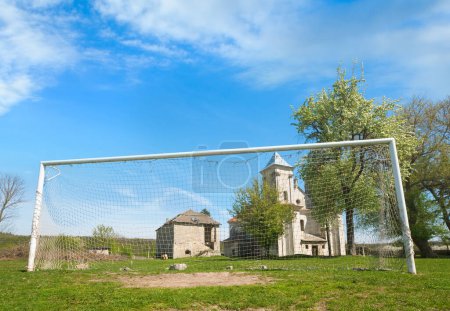 Photo for Church of Annunciation of Blessed Virgin Mary (Sydoriv village, Ternopil region, Ukraine, Built in 1726-1730) and football goal. - Royalty Free Image