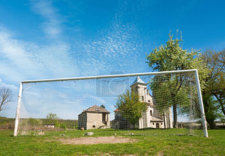 Photo for Church of Annunciation of Blessed Virgin Mary (Sydoriv village, Ternopil region, Ukraine, Built in 1726-1730) and football goal. - Royalty Free Image