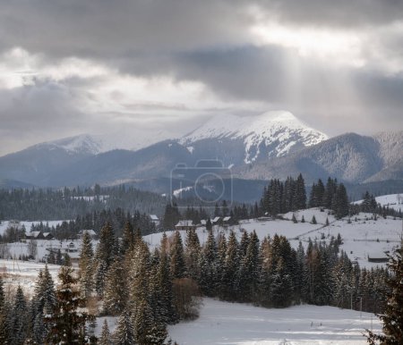 Foto de Invierno remoto pueblo alpino de montaña afueras, colinas rurales, arboledas y tierras de cultivo. - Imagen libre de derechos
