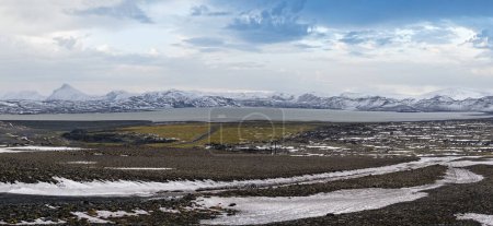 Foto de Islandia tierras altas otoño vista ultraancha. Campos de lava de arena volcánica en primer plano. Lago Hrauneyjalon y montañas cubiertas de nieve volcánica en lejos. - Imagen libre de derechos